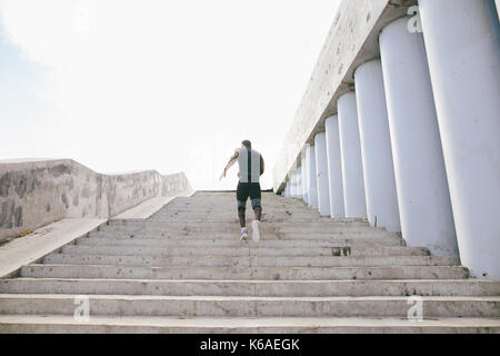 Nero Africa sportivo in corsa verso l'alto con energia sul stadium bleachers Foto Stock