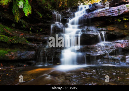 Liscio sfocata del flusso di acqua che scorre verso il basso le rocce di arenaria in Australian central coast ancien Gondwana rainforest gumtree park - Somersby cade Foto Stock