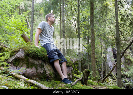 Metà adulto uomo caucasico all'aperto nel tranquillo rilassante foresta su roccia modello di rilascio: Sì. Proprietà di rilascio: No. Foto Stock