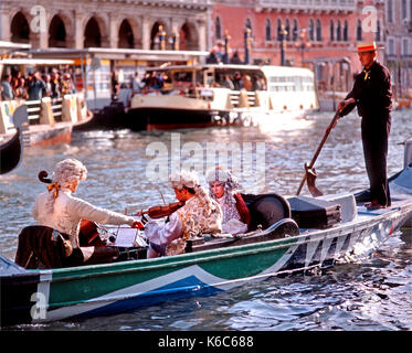 Venezia, Veneto, Italia. I musicisti in costume giocando in una gondola durante il carnevale sul Canal Grande Foto Stock