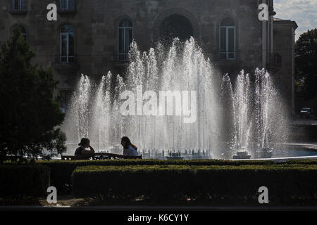 Due femmine seduti sui banchi accanto a una fontana nel centro di Gori, Georgia. Foto Stock