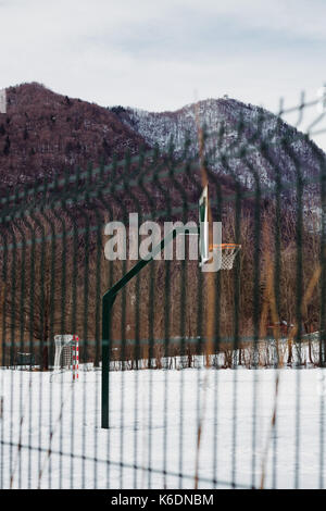 Recinzione metallica con sfocato pallacanestro in inverno. Foto Stock