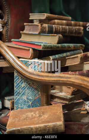 Vintage poltrona in stile barocco con vecchi libri contro la cortina verde Foto Stock