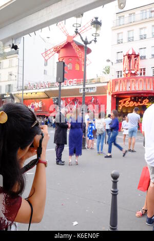 Un turista prende una foto della folla fuori del Moulin Rouge a Montmartre, Parigi Foto Stock