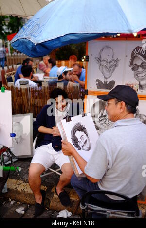 Un artista di strada completa una caricatura di un turista in Place du Tertre a Montmartre, Parigi Foto Stock