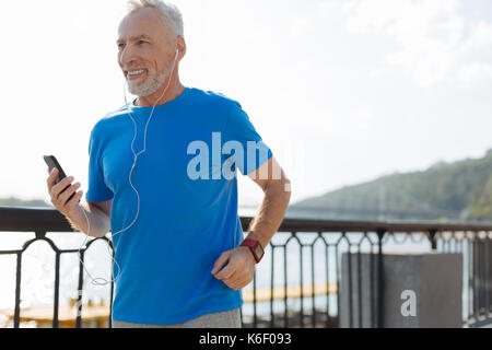 Allegro senior uomo jogging e ascolto di musica Foto Stock