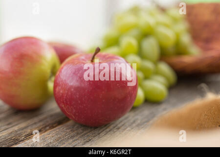 Primo piano di un tavolo d'annata con mele in primo piano e uvetta sullo sfondo. Decorazione di una vita semplice all'aperto. Foto Stock