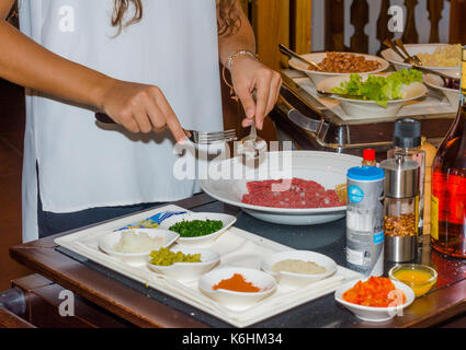 Lo chef femmina preparazione bistecca alla tartara in cucina con una salsa speciale in ristorant Foto Stock