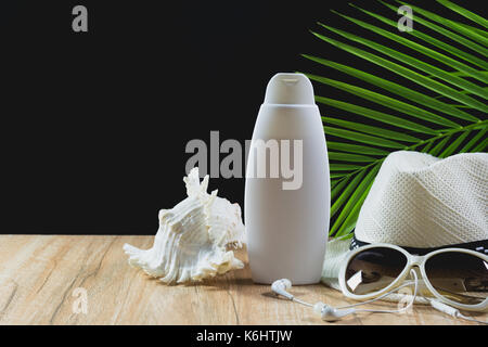 Roba da viaggio essenziali elementi di viaggio. occhiali da sole e cappello bianco e crema di protezione solare bottiglia sul tavolo di legno dello sfondo. Foto Stock