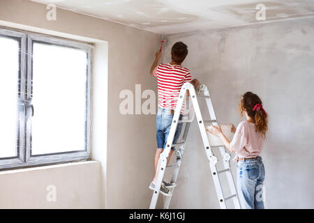 Coppia giovane pittura pareti nella loro nuova casa. Foto Stock