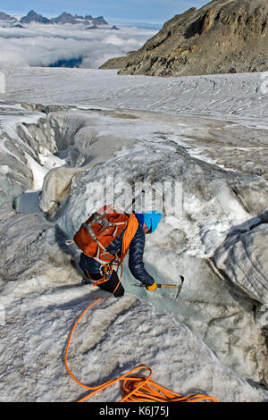 Alpinista esaminato un crepaccio sul plateau du trient, Vallese, Svizzera Foto Stock