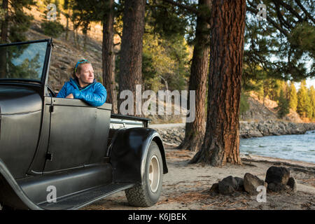 Donna seduta nel rinnovato carrello guardando il tramonto sul Lago Payette, McCall, Idaho, Stati Uniti d'America