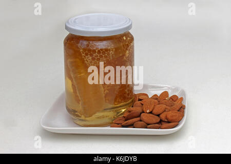 Miele di favo in barattolo di vetro con mandorle crude Foto Stock