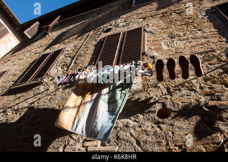 Biancheria stesa ad asciugare su una linea in alto al di fuori della finestra di una casa a san gimignano, toscana italia Europa UE Foto Stock