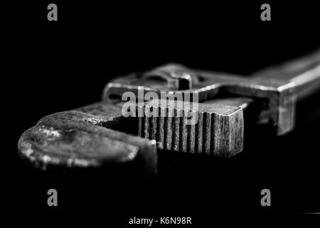 Rusty, vecchia bottega chiavi. chiavi idrauliche su una tavola nera in un workshop. Foto Stock