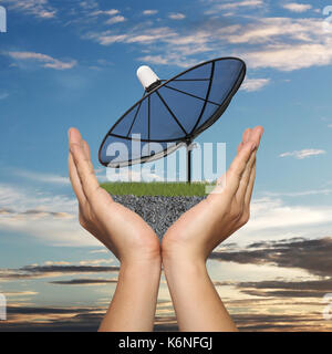 Nero piatto satellite in mano di imprenditore su sfondo al tramonto,concetto di comunicazione di dati. Foto Stock