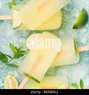 Estate rinfrescante limonata popsicles con lime e menta con scaglie di ghiaccio su sfondo blu, vista dall'alto, quadrato ritaglia Foto Stock