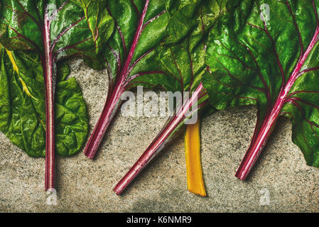 Flat-lay di foglie fresche di bietole su calcestruzzo sfondo di pietra, vista dall'alto, composizione orizzontale. Pulire mangiare, vegetariane e vegane, pile alcaline di Foto Stock