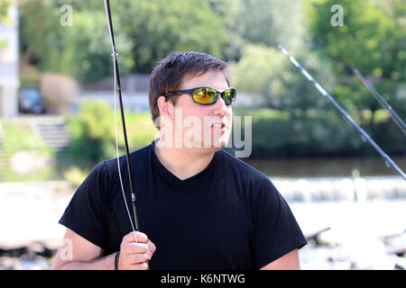 Giovane uomo con la canna da pesca pesca in un fiume in Baviera Foto Stock