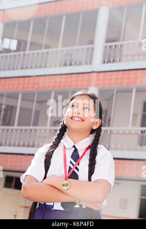 Dream 1 Indian School bambina Medaglia Vittoria e il braccio attraversata in piedi nel cortile della scuola Foto Stock