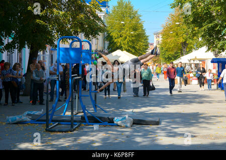 Un uomo in piazza fa esercizi ginnici su barre irregolari e un traversino. Giorno della città. zhitomir dell'anno 1133. settembre 2017, Ucraina. Foto Stock