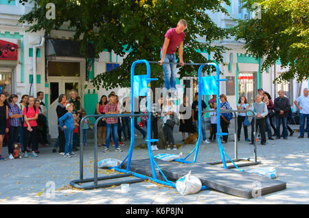 Un uomo in piazza fa esercizi ginnici su barre irregolari e un traversino. Giorno della città. zhitomir dell'anno 1133. settembre 2017, Ucraina. Foto Stock