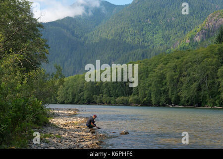 Un giovane maschio il panning per oro in un fiume. Foto Stock