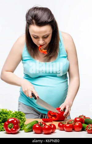 Donna incinta la preparazione di insalata di verdure in cucina Foto Stock