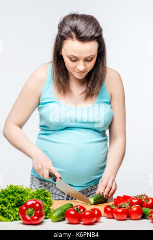 Ritratto verticale di una donna incinta durante la preparazione di una insalata di verdure Foto Stock