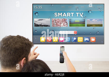 Vista posteriore giovane guardando smart tv sul televisore di casa. Foto Stock