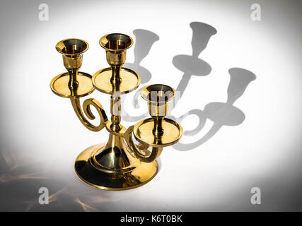 Candelabro d'oro su sfondo bianco con ombre di close-up. Foto Stock