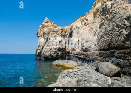 Una scogliera lungo la costa maltese, che mostra le caratteristiche di erosione del mare e la scogliera di recessione. Taglio a onda la piattaforma a livello del mare e le crepe e massi. Foto Stock