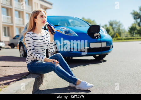 Piuttosto giovane donna seduta nella parte anteriore della sua automobile Foto Stock