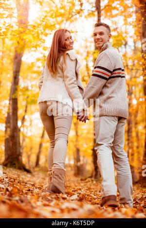 Bella coppia sorridente passeggiate nella foresta di sole in autunno colori. guardando la telecamera posteriore, VEW. Foto Stock