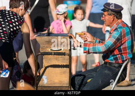 Sarbinowo, Polonia - Agosto 2017 : street busker con un paio di occhiali da sole e cappello giocando su un vecchio legno strumento organette Foto Stock