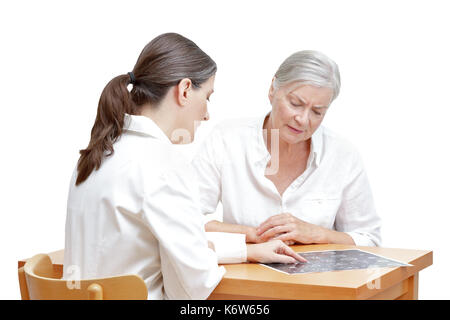 Medio di sesso femminile di età compresa tra medico mostrando il suo senior un paziente MRI del suo capo, isolato su sfondo bianco Foto Stock