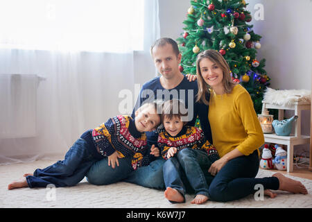 La famiglia felice avendo divertimento a casa natale ritratto di famiglia nella parte anteriore dell'albero di natale Foto Stock