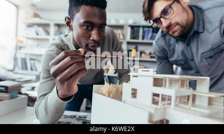 Due architetti maschi in ufficio a discutere il progetto di costruzione. Giovani uomini che lavorano insieme su un nuovo modello di edificio. Foto Stock