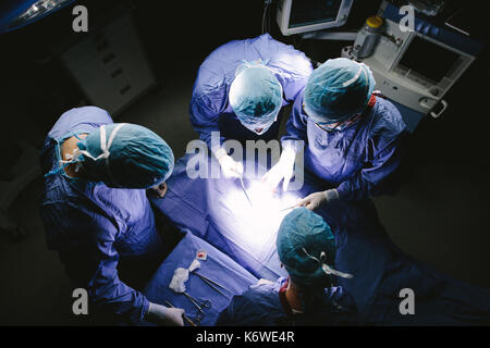 Vista Top Shot di team di chirurghi di eseguire l'intervento chirurgico nel funzionamento del teatro. Il gruppo di medici in ospedale teatro operativo. Foto Stock