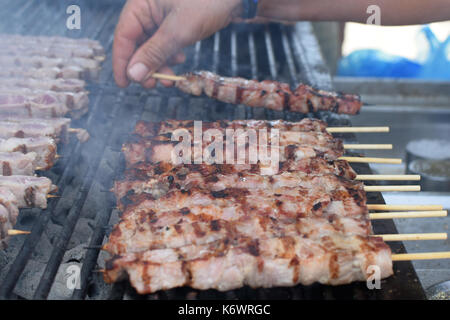 L'uomo la tostatura souvlaki spiedini di carne sul grill caldo. Foto Stock