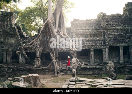 Ragazza con cappello con un abito rosso a piedi attorno al tempio di Preah kahn in Angkor, Siem Reap, Cambogia Foto Stock