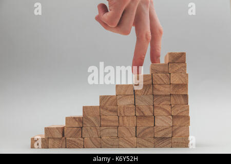 Persone mano a camminare su un insieme di blocchi di legno. lo sviluppo del business e la crescita concetto Foto Stock