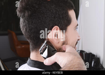 Chiusura del giovane uomo avente un taglio di capelli con tosatrici. Foto Stock