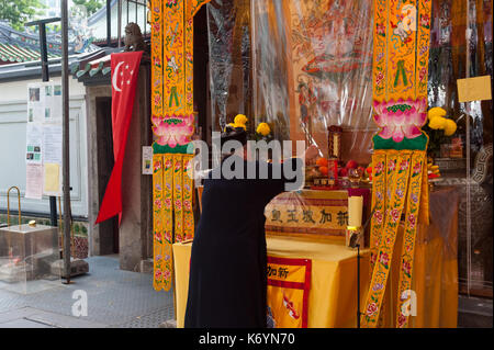 03.09.2017, Singapore, Repubblica di Singapore, in asia - una femmina di sacerdote accende bastoncini di incenso davanti a un altare presso il Thian Hock Keng Temple. Foto Stock