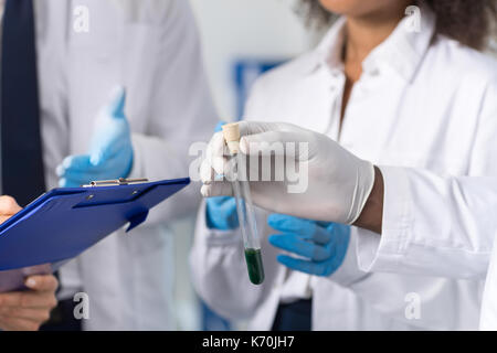 Un gruppo di scienziati del laboratorio esaminando provetta rendendo note discutere di sperimentazione o di ricerca di indossare strati di protezione guanti, lavoratori in lab Foto Stock