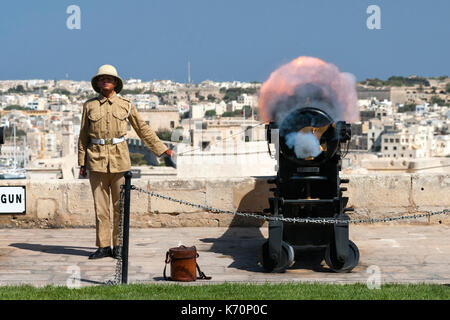 Un giovane gunner incendi per Malta il cannone di mezzogiorno per contrassegnare l'ora di mezzogiorno. Il cannone di mezzogiorno salute è una vecchia tradizione navale che re-è stato istituito nel 2004 e OC Foto Stock