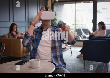 Imprenditore dai colleghi indossando la realtà virtuale simulatore presso la tabella in office Foto Stock