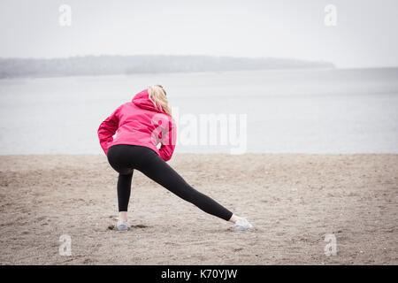 Vista posteriore della donna che esercitano in spiaggia Foto Stock