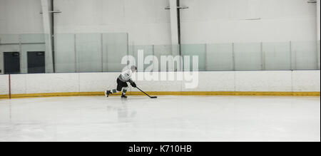 Lettore maschio praticare hockey su ghiaccio al pattinaggio. Foto Stock