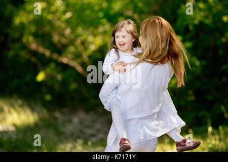 Baby con down sydrome godendo di gioco all'aperto Foto Stock